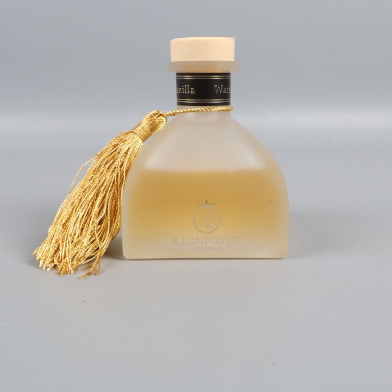 Närbild på frostad doftflaska och svart etikett