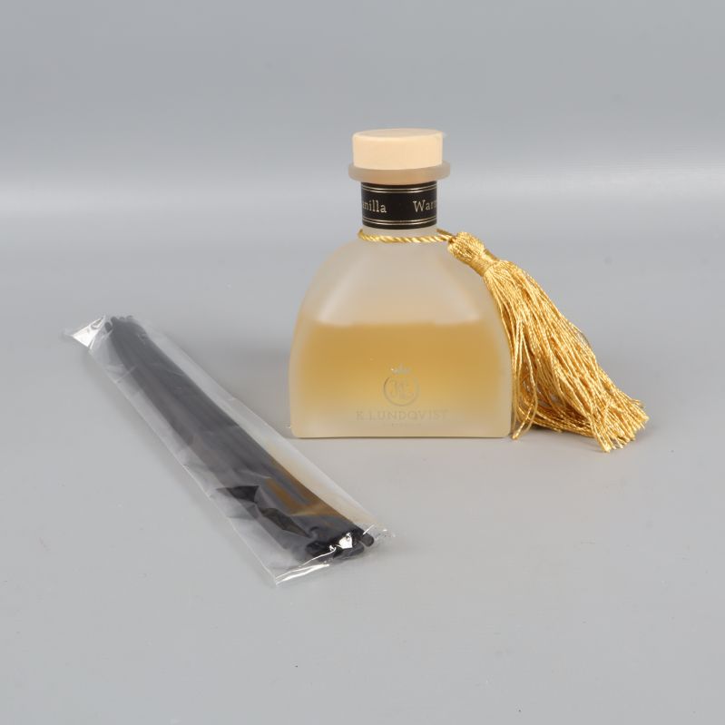 Frostad glasflaska med tofs och oöppnade doftpinnar