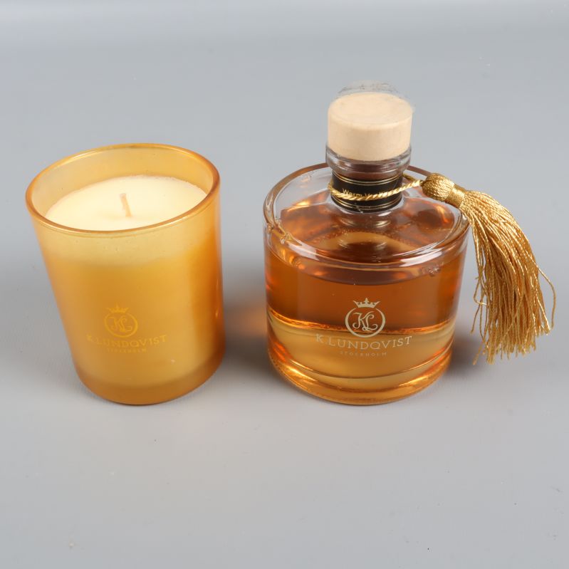 Närbild på doftljus och rund flaska med tofs