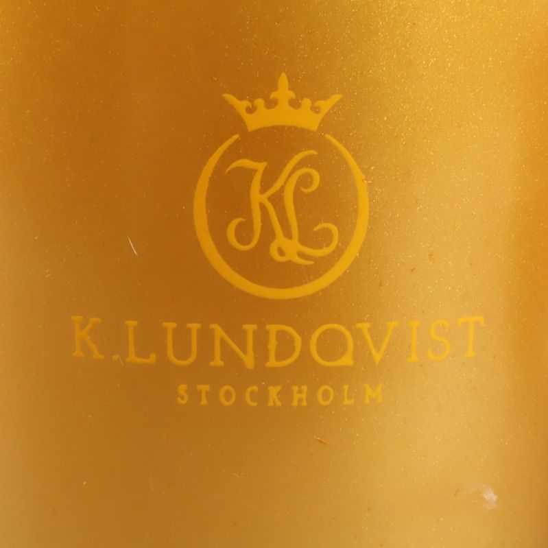 Närbild på logotypen K.Lundqvist på guldfärgat ljus