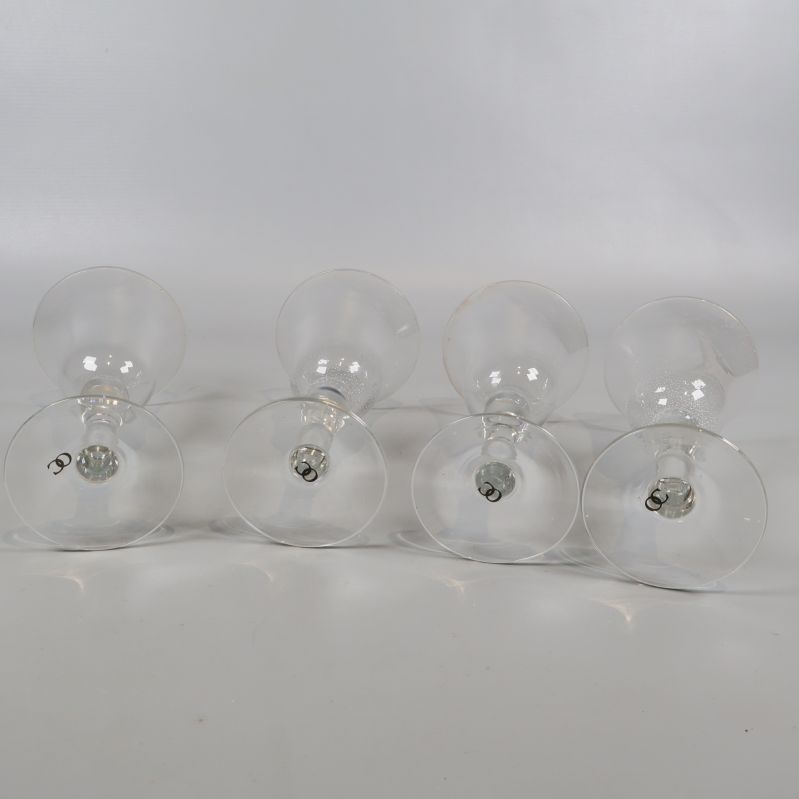 Fyra vinglas liggande på sidan på vitt underlag