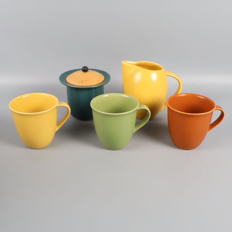 Fem delar i set med kanna, burk och tre muggar i olika färger