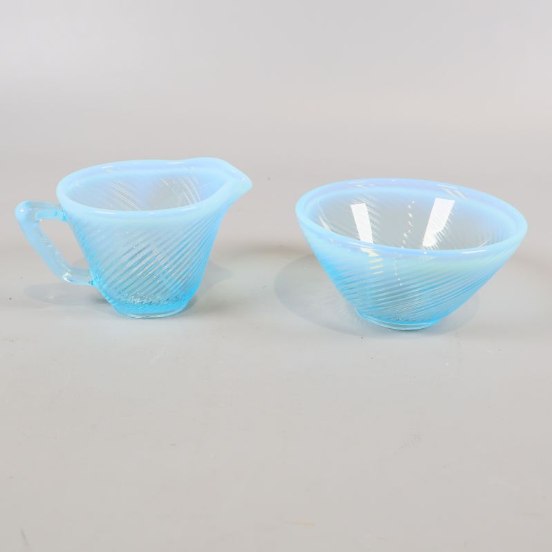 Blå gräddkanna och sockerskål i glas från sidan