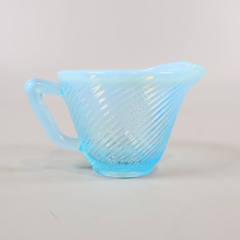 Närbild på blå gräddkanna i glas med spiraldesign