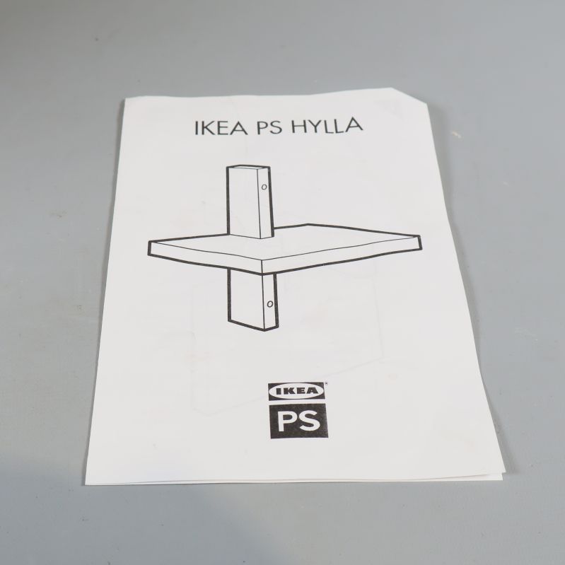 Bruksanvisning IKEA PS HYLLA ligger på ett bord