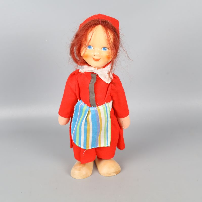 Stående tomteflicka med röd dräkt och randigt förkläde