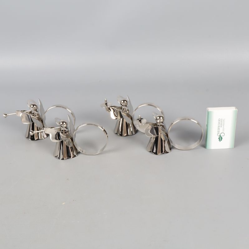 Fyra ängel-servettringar i metall bredvid tändsticksask