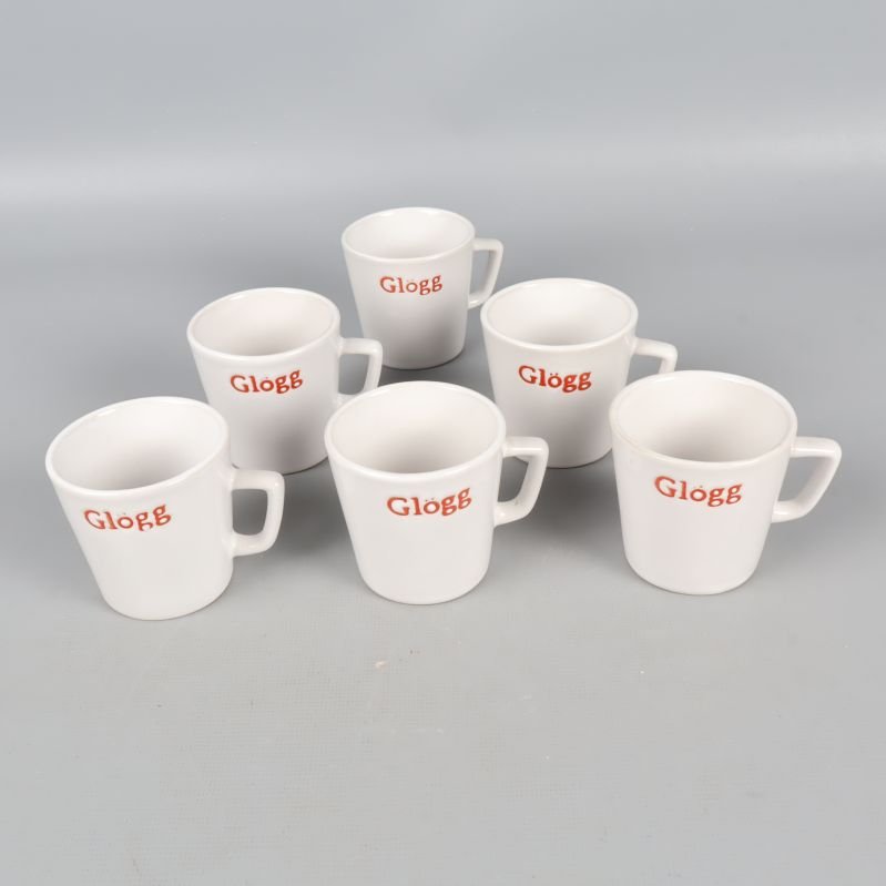 Sex vita glöggmuggar med röd text arrangerade framför grå bakgrund