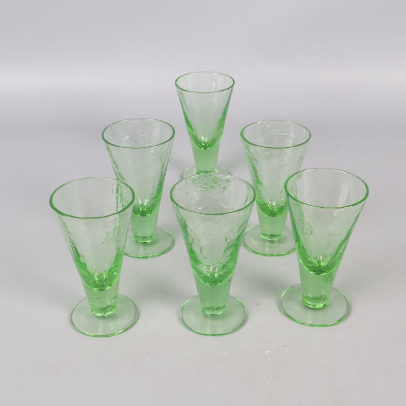 Sex gröna likörglas i grupp på vit bakgrund