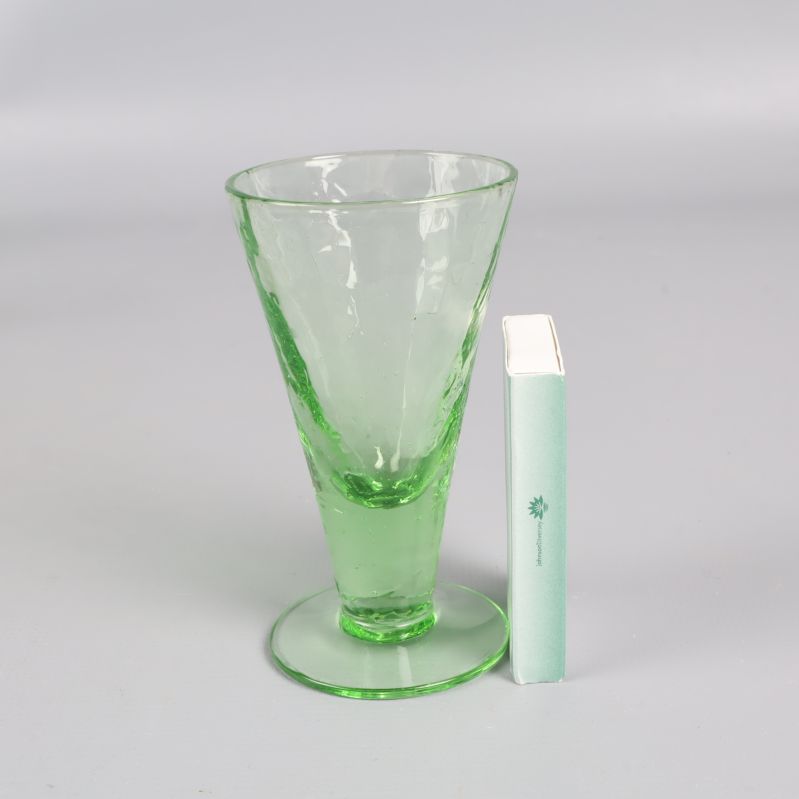 Grönt likörglas bredvid tändsticksask för storleksjämförelse