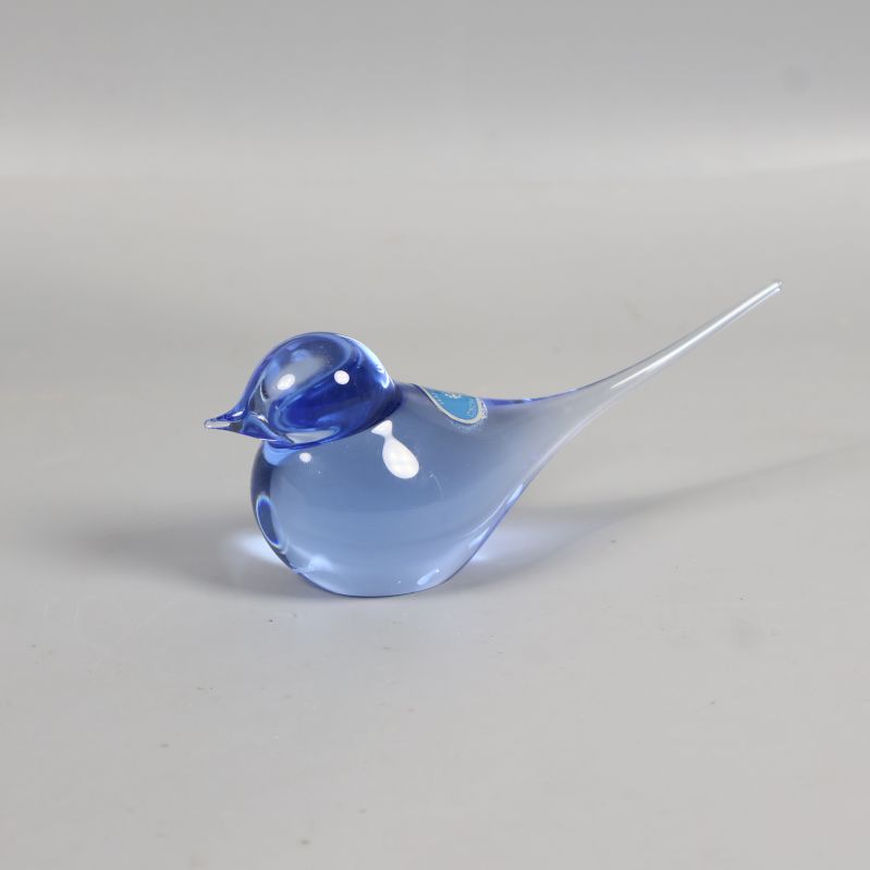 Blå dekorationsfågel i glas med lång spetsig stjärt