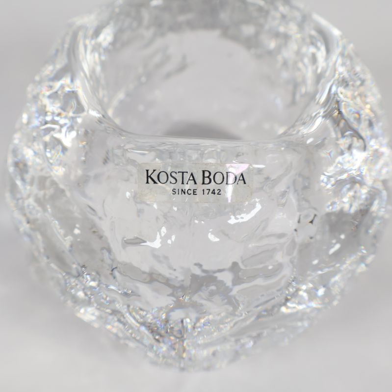 Närbild på Kosta Boda logotyp på glasljushållare