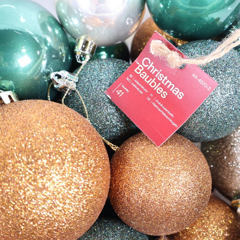 Närbild på glittriga julgranskulor med röd etikett