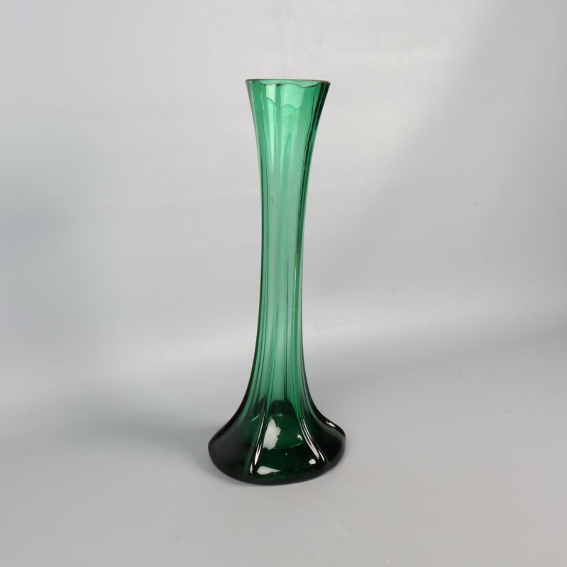 Grön glasvas fotograferad snett framifrån mot vit yta