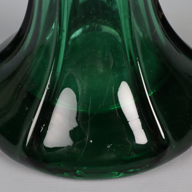 Närbild på basen av grön glasvas med repor