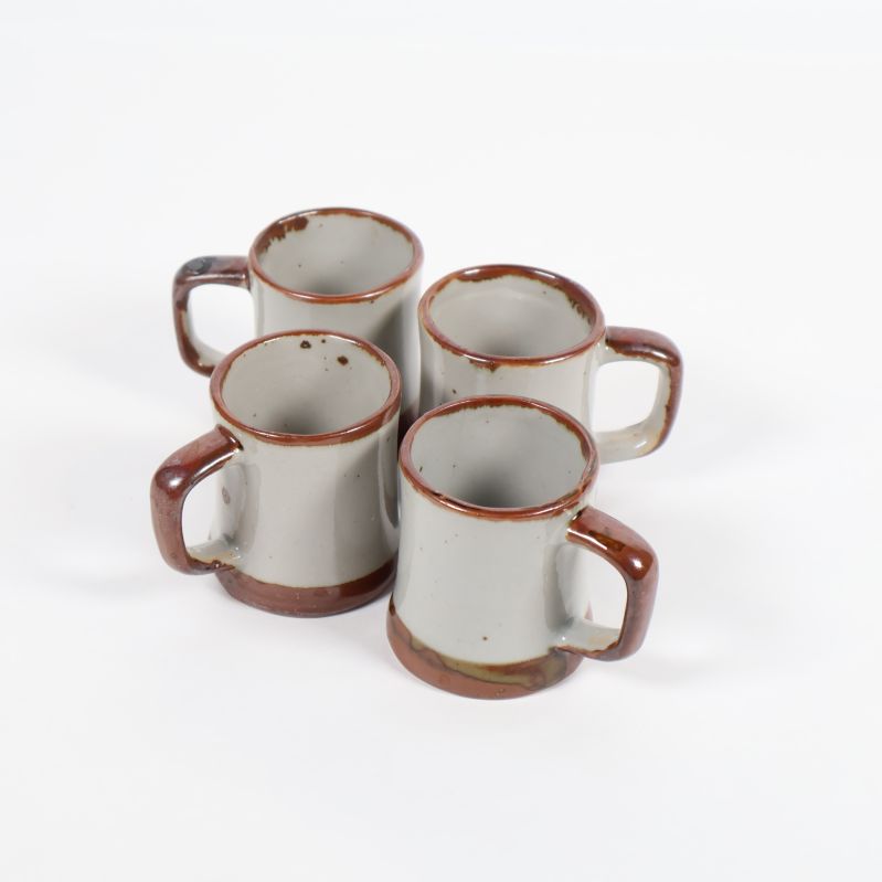 Fyra små vitbruna keramikkoppar står grupperade