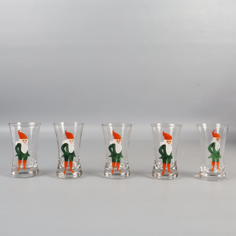 Fem snapsglas med tomtemotiv i rad mot ljus bakgrund