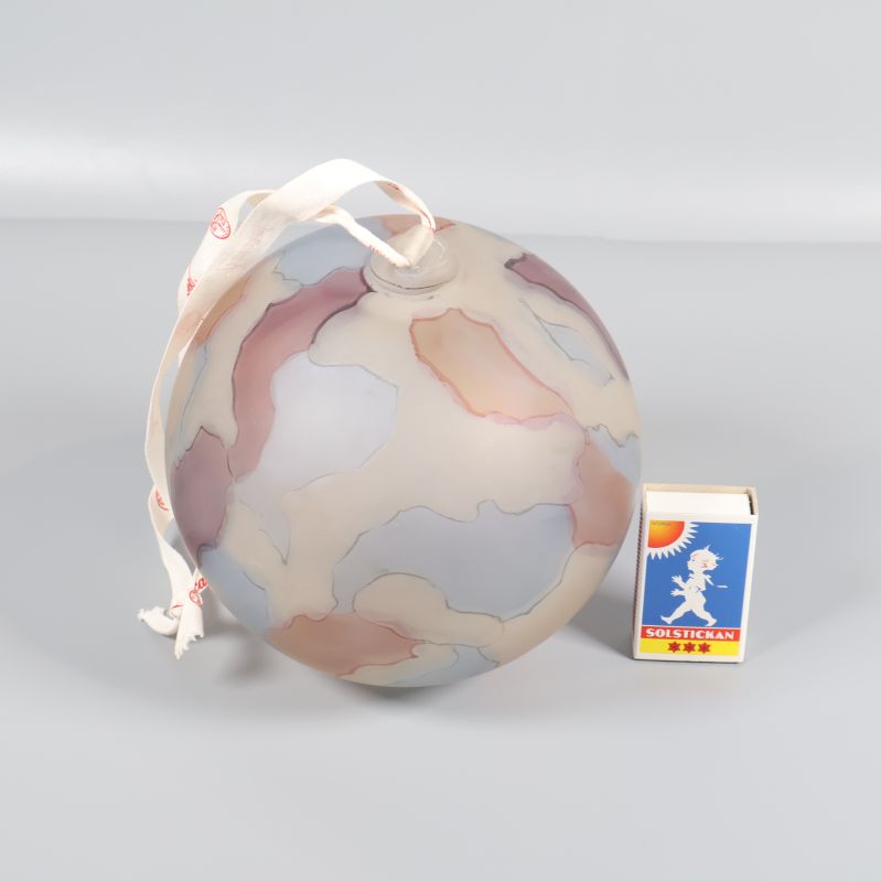 Glaskula i pastelltoner bredvid tändsticksask