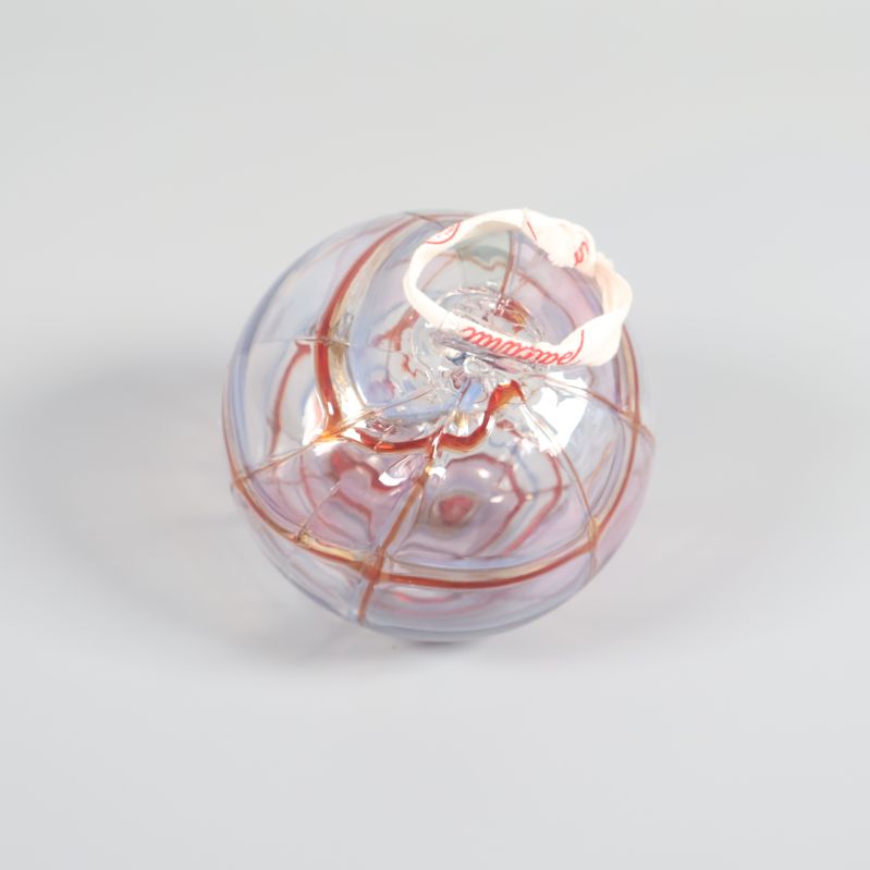 Glaskula med färgade ränder och vit rosett på toppen