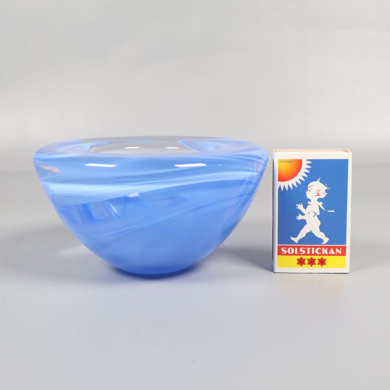 Blå ljusstake i glas bredvid tändsticksask för storleksjämförelse