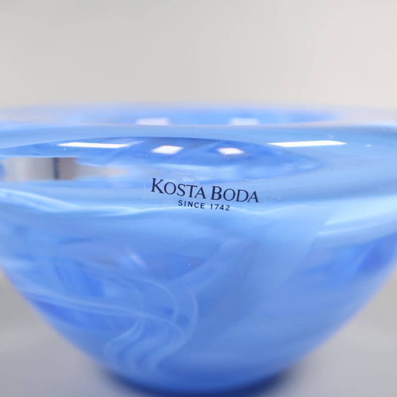 Kosta Boda-logga på blå glasljusstake i närbild