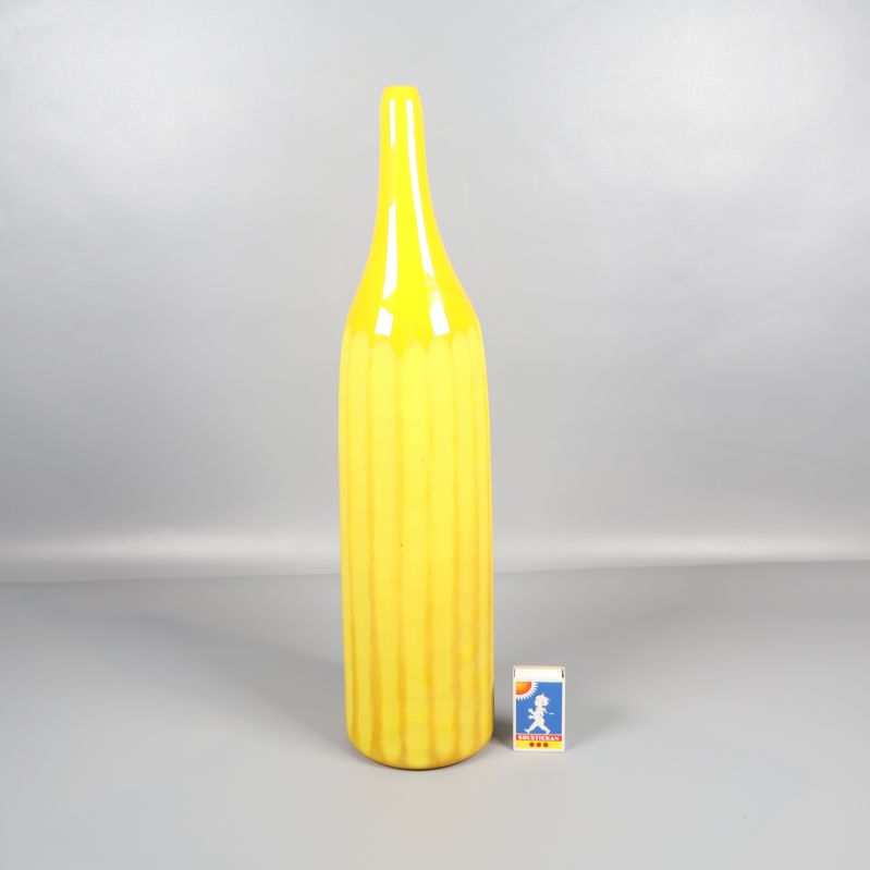 Hög gul vas jämte tändsticksask