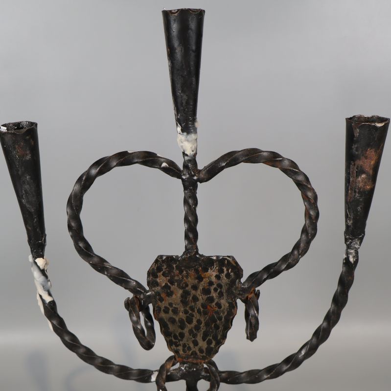 Närbild på ljusstakens tre ljushållare i svart smide