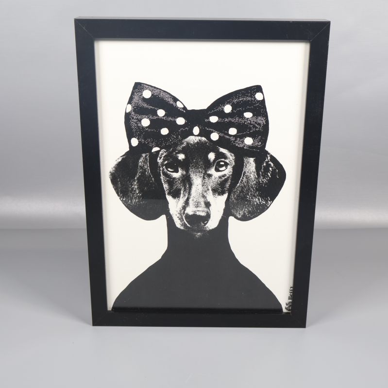 Tavla med svartvitt hundmotiv och prickig rosett