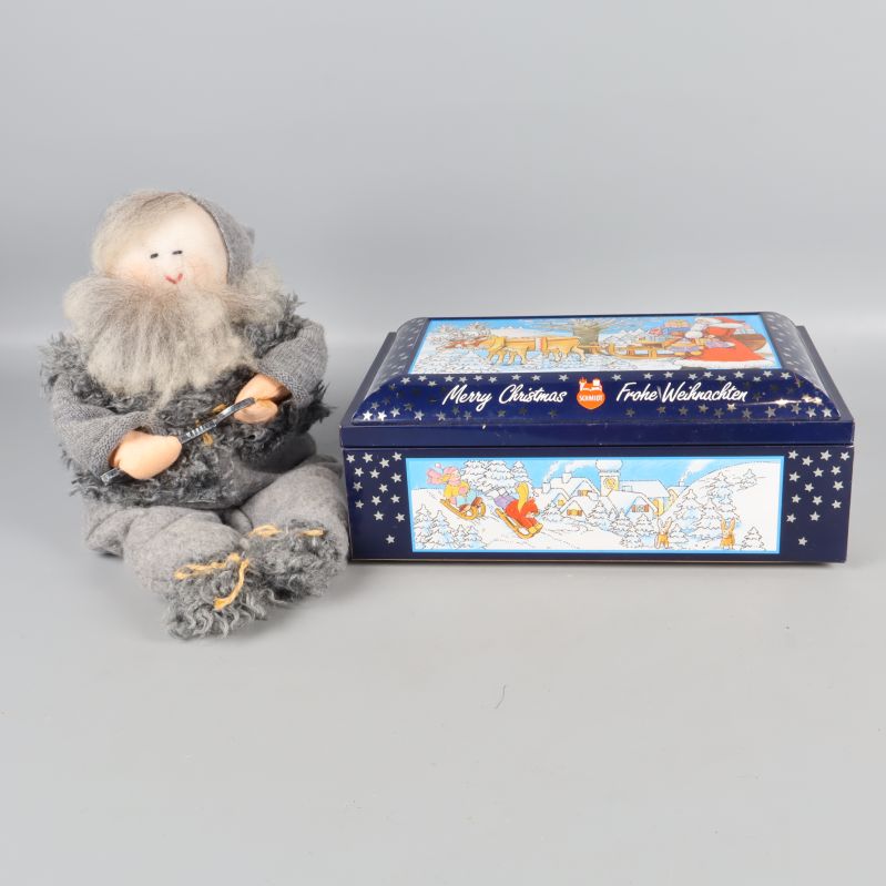 Mjuk tomtefigur i grått och blå metallburk med julmotiv