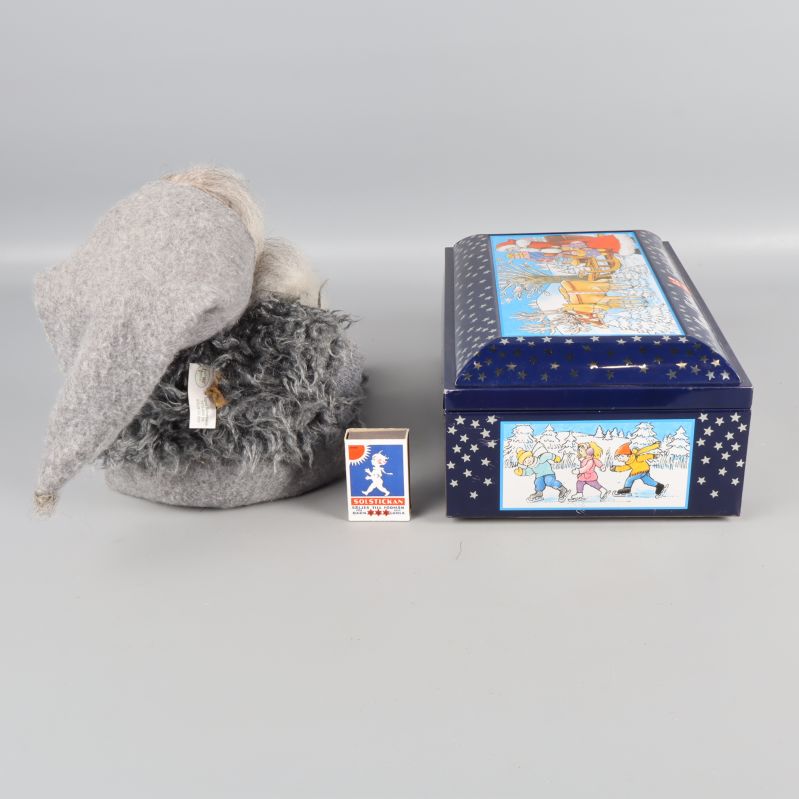 Tomtefigur från sidan och blå burk med tändsticksask som storleksreferens