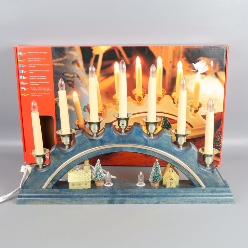 Adventsljusstake i blått trä med tända plastljus och bymotiv