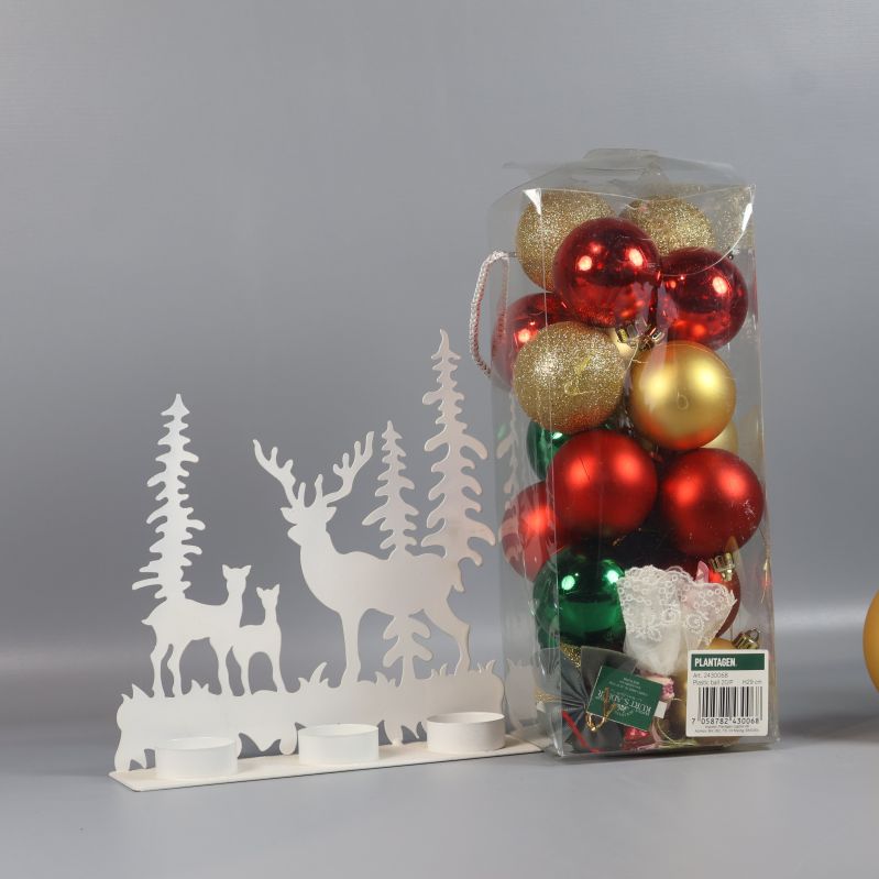 Vitt ljusstake med hjortfigurer och julkulor i bakgrunden