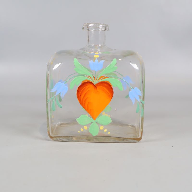 Framifrån vy av snapskaraff med hjärtmotiv och blommor