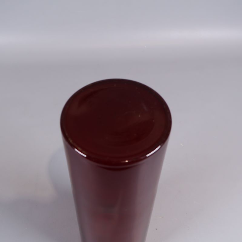 Undersida av cylinderformad röd glasvas som visar botten