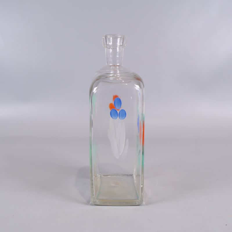 Baksida av rektangulär glasflaska med blommotiv