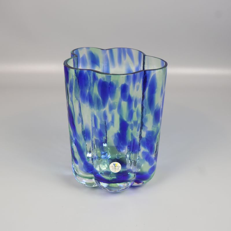 Vas i blått glas med gröna och vita inslag sedd framifrån