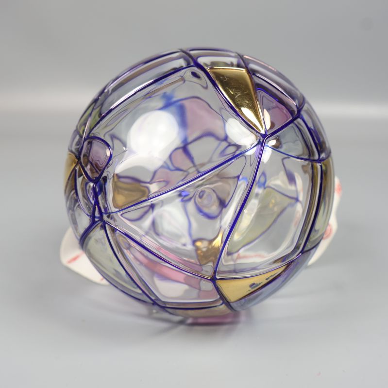 Julkulans baksida med geometriska färgdetaljer i lila och guld