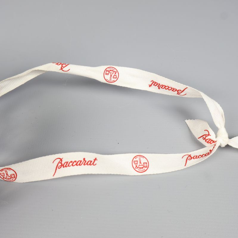 Vitt band med röd text Baccarat och logotyp i närbild