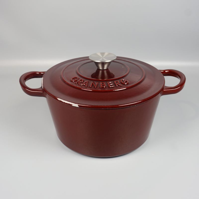 Mörkröd gryta med lock och två handtag framifrån