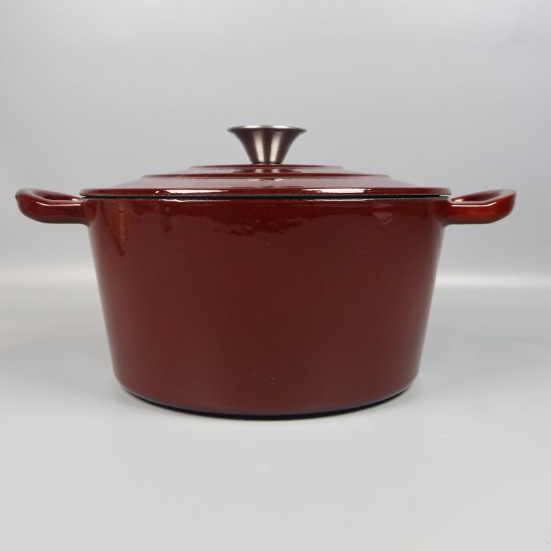 Sida av mörkröd gryta med lock och handtag synliga