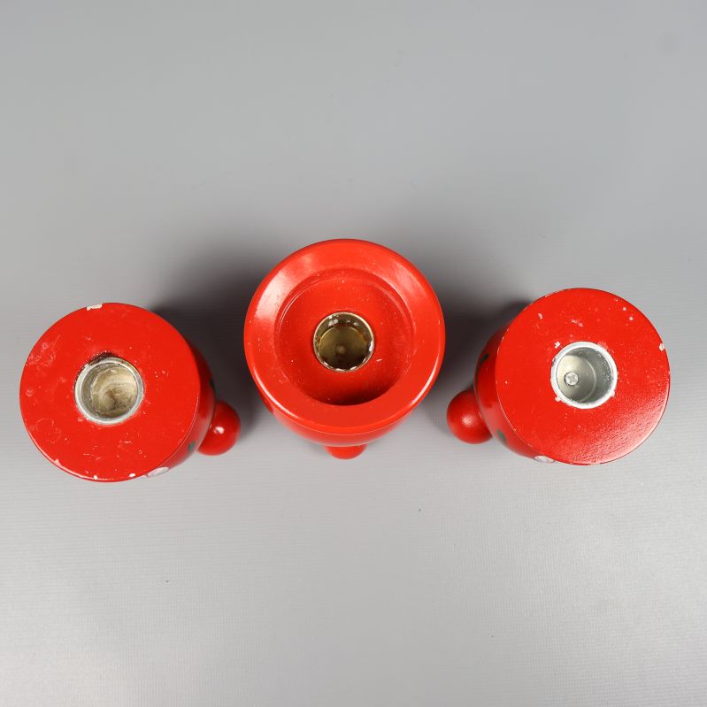 Öppningar för ljus på tre röda träljusstakar ovanifrån