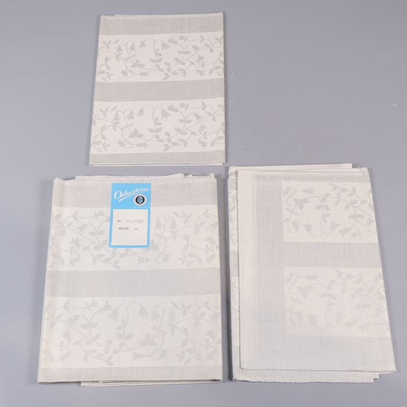Tre vikta vita linservetter med blommotiv