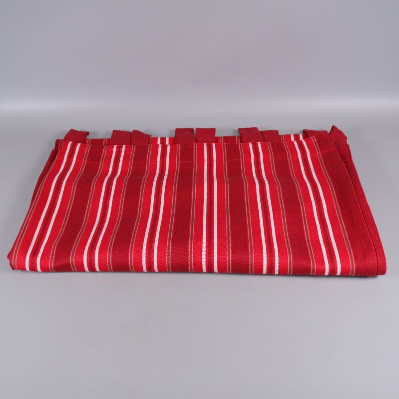 Röd gardin med vita ränder ligger vikt