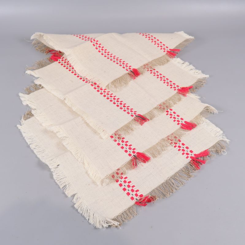 Fyra vikta tygservetter med fransar och röda detaljer