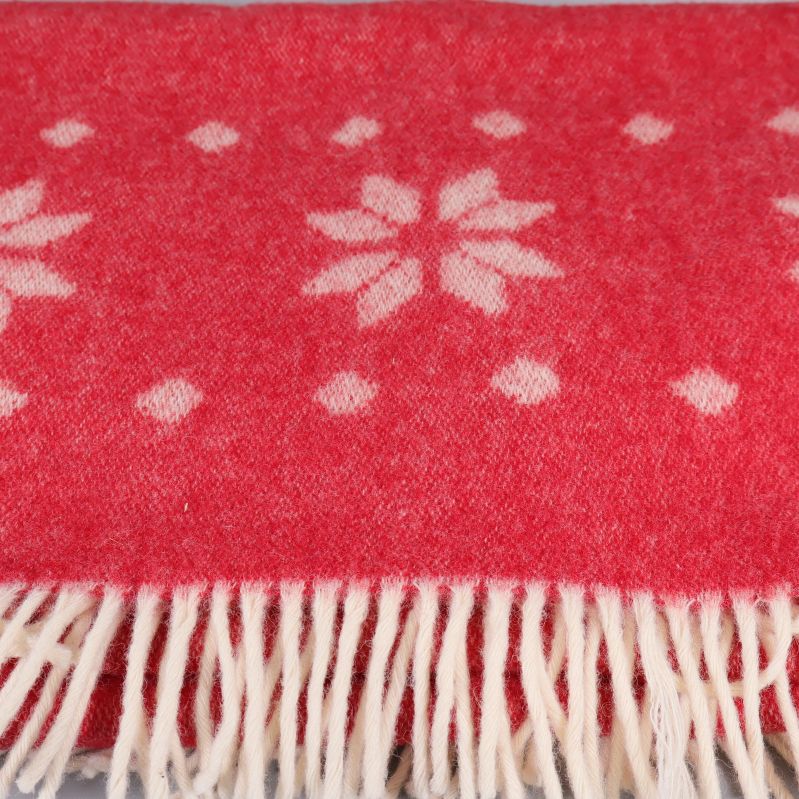 Närbild på snöstjärnmönster och vita fransar på pläd