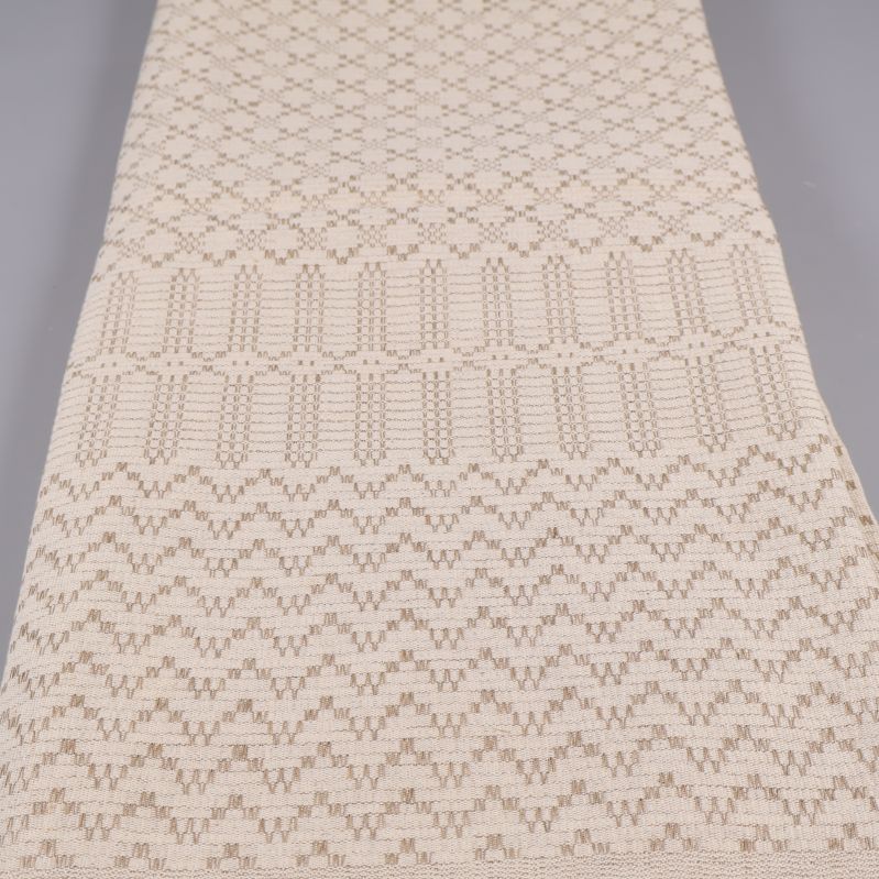 Duk i beige med tydligt invävt mönster längs hela ytan