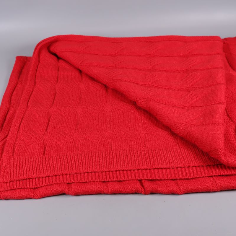 Stickad röd pläd med vikt hörn och ribbad kant