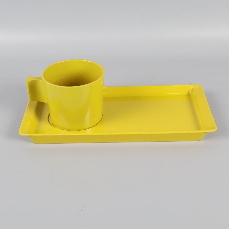Gul/Grön kopp och bricka visade snett bakifrån på vit bakgrund