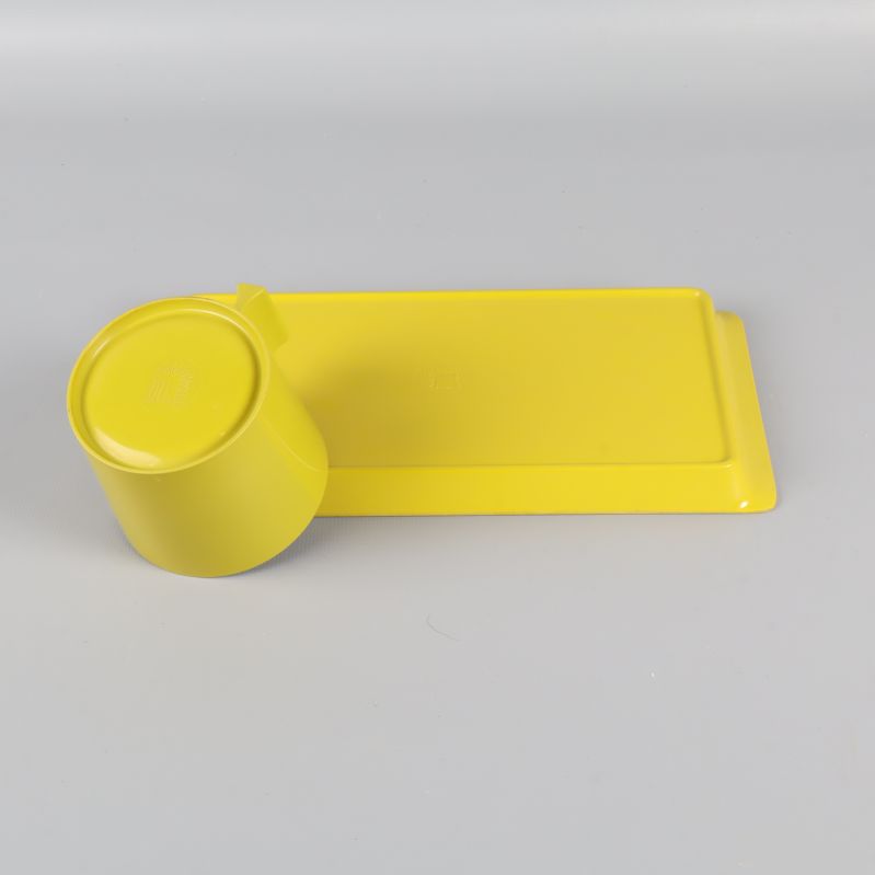 Undersidan av gul/grön kopp och bricka i plast