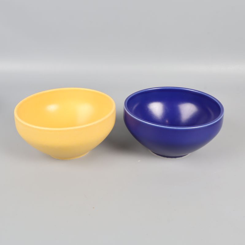 Två skålar i gul och blå framför grå bakgrund